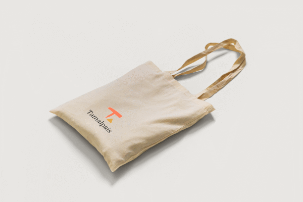 Eco-friendly tote bag with Tamalpais branding, laid flat on white background with handles arranged casually.